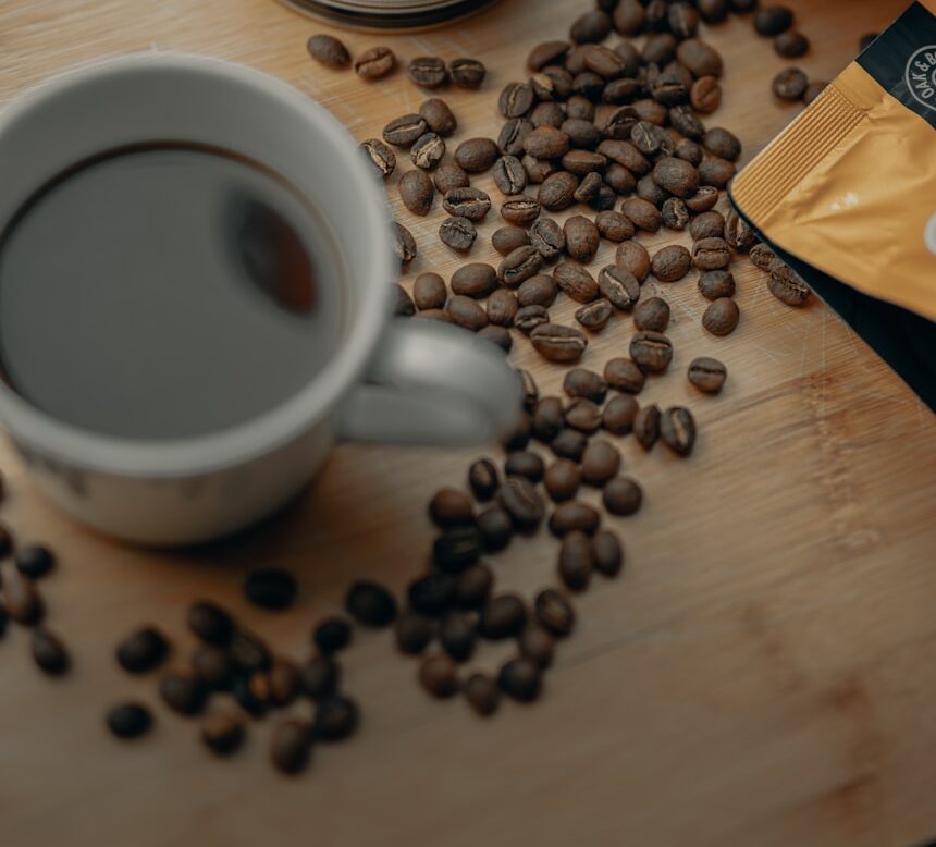 white ceramic mug with coffee beans on brown wooden table